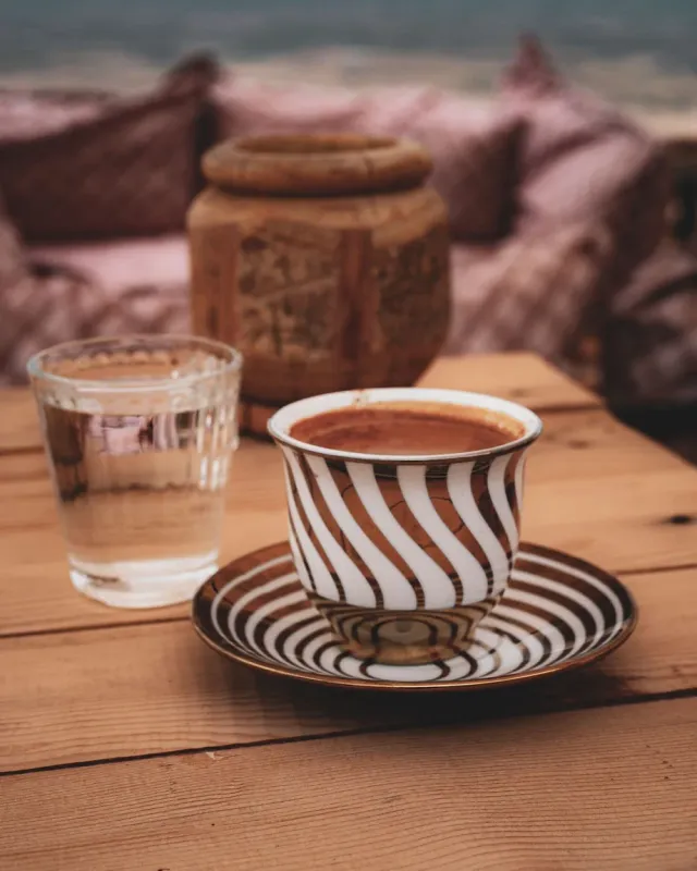 A Turkish coffee and a glass of water on a rustic cafe table