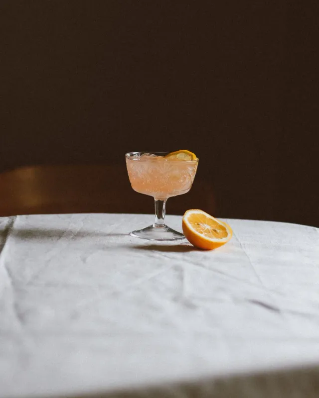 A citrus mocktail in a coupe in dramatic low light