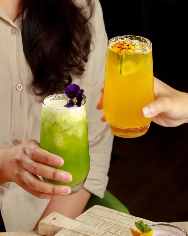 Two people toasting colorful non-alcoholic drinks