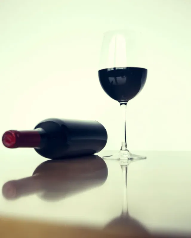 A glass of red wine and a reclining bottle
